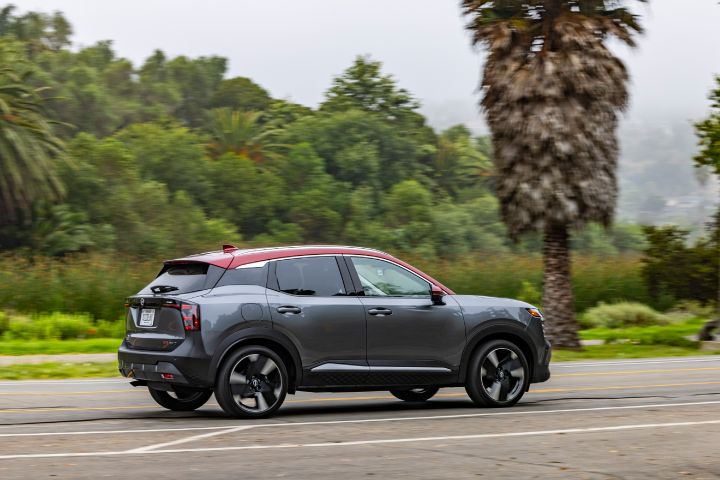 Right rear 3/4 view of a silver 2026 Nissan Kicks with trees behind.