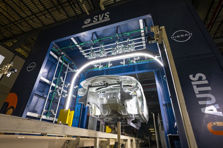 An AUTIS structure holds a car body frame in the air with a tube light over top of it.