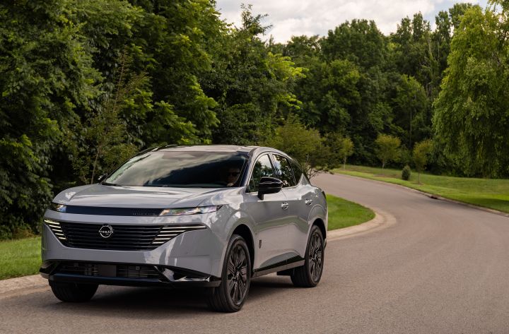 Front left 3/4 view of the 2027 Nissan Murano Dark Armor parked along a curving, tree-lined road.