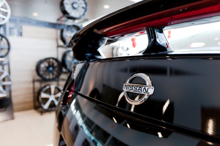 Gros plan du logo Nissan sur une voiture noire brillante.