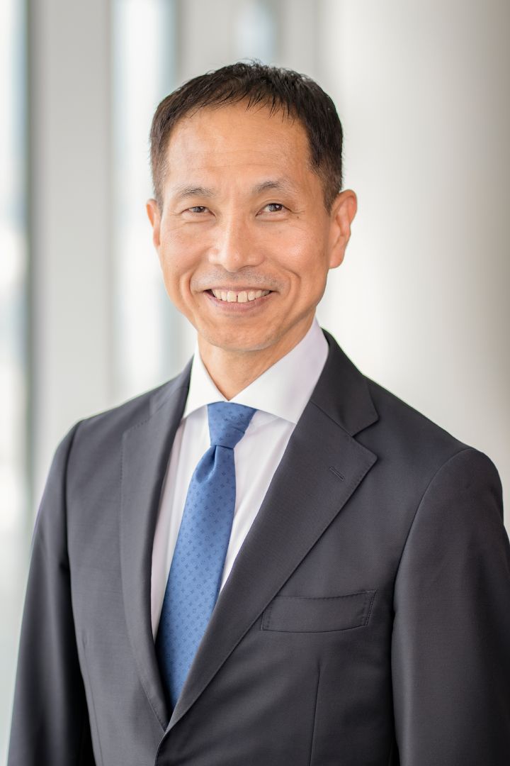 Portrait of Toru Ihara with navy blue suit, tie and NISSAN corporate pin (smiling)