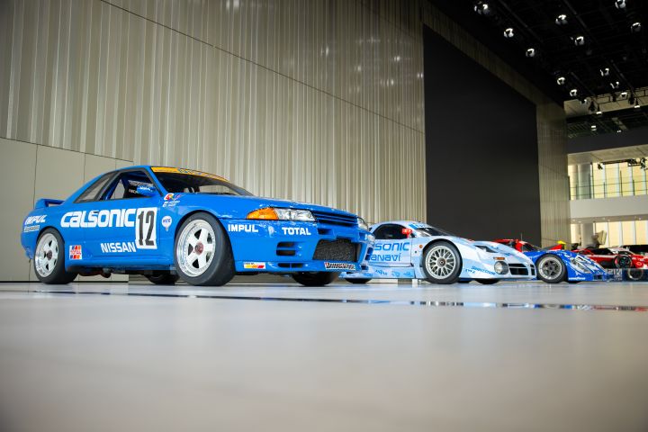 A line-up of three iconic NISMO race cars with blue GT‑R race car inset with "Calsonic" and number 12 along its side.