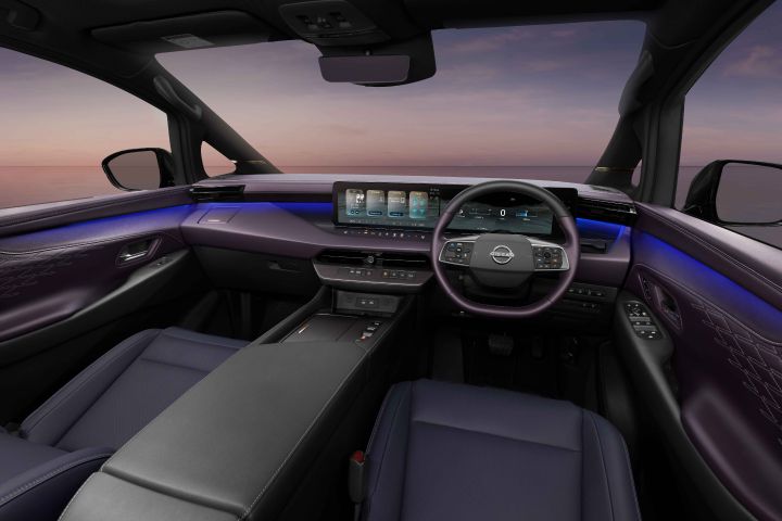 The front cabin of the Elgrand interior. A modern dashboard with multiple screens and a steering wheel is visible, highlighting the spacious and advanced interior.