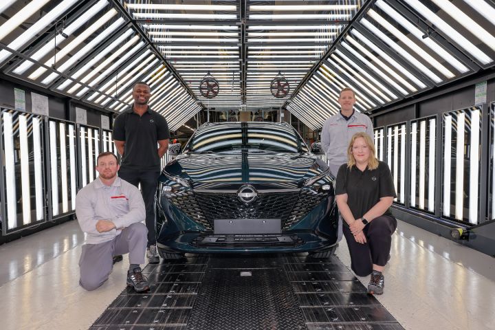 Vier Nissan Mitarbeiter knien und stehen neben einem dunkelgrünen neuen Nissan Qashqai auf der Produktionslinie des Nissan Weks in Sunderland
