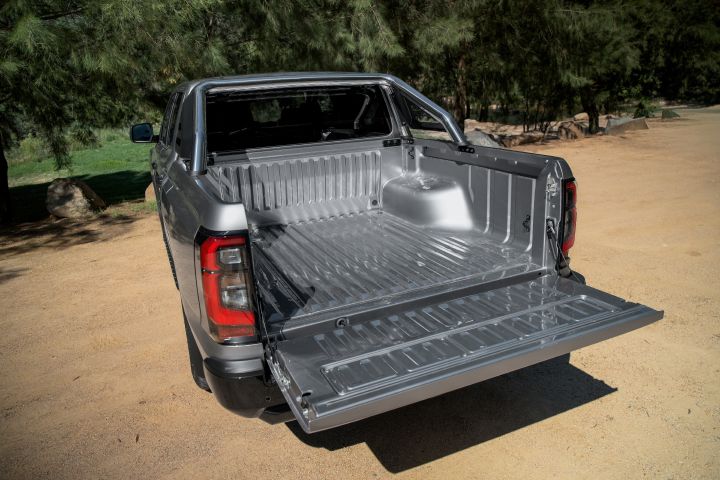 2026 Nissan Navara ST dual cab ute finished in Summit Silver shown from the rear with the tailgate lowered, exposing the empty cargo tub and ribbed bed floor.