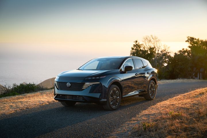 Front left 3/4 angle of a 2025 Nissan Murano parked on a grassy hill, the headlights are on.
