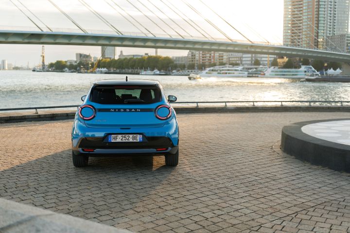 Heckansicht eines Nissan Micra in der aufgehenden Sonne, im Hintergrund liegen Passagierschiffe im Wasser und darüber spannt sich eine Brücke