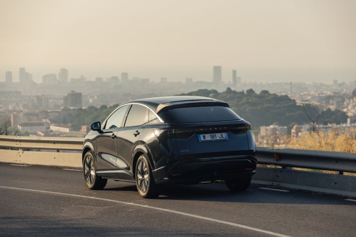Blick von schräg hinten auf das fahrende, schwarz lackierte Nissan Ariya Concept mit Solartechnologie