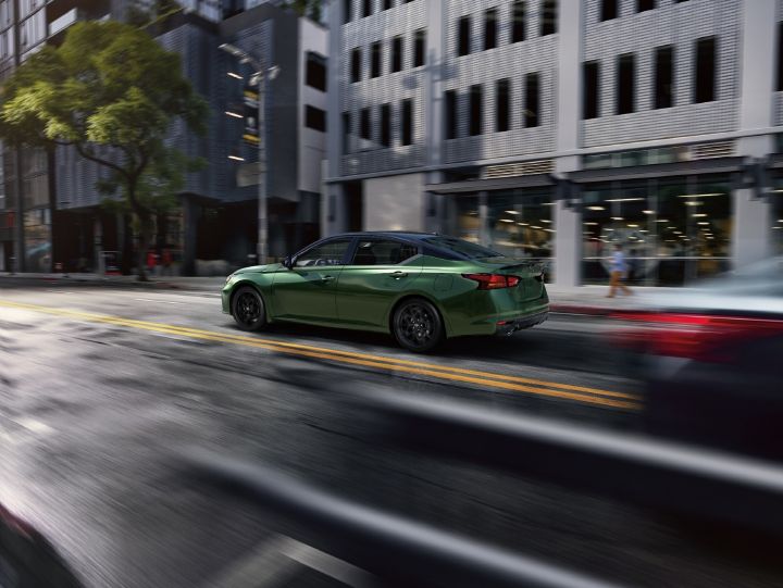 Angled rear view of the 2026 Nissan Altima driving along a city street.