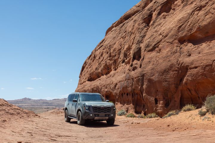 Front right 3/4 view of the 2026 Nissan Armada parked on a clay road with red rock behind.
