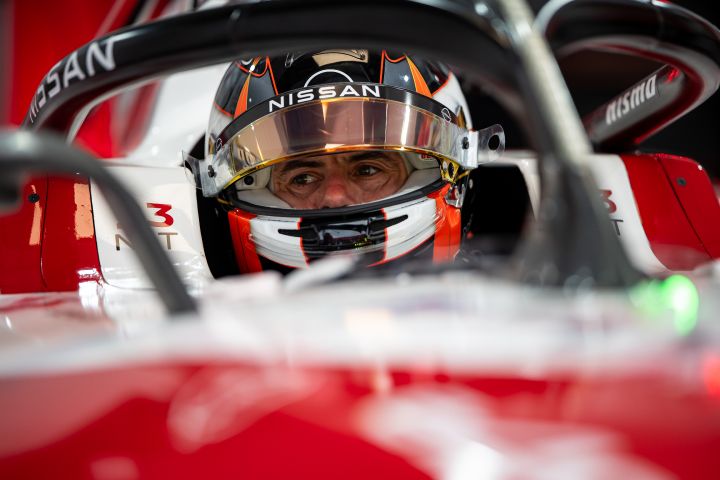 Norman Nato mit aufgesetztem Helm und hochgeklapptem Visier sitzt im Nissan Formel E Rennwagen mit der Startnummer 23 in der Teamgarage.
