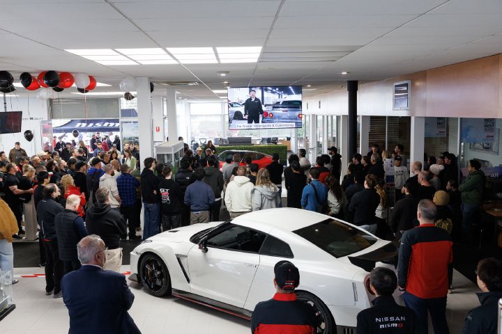 A crowd watching Sanada-san from NMC present via TV screen.