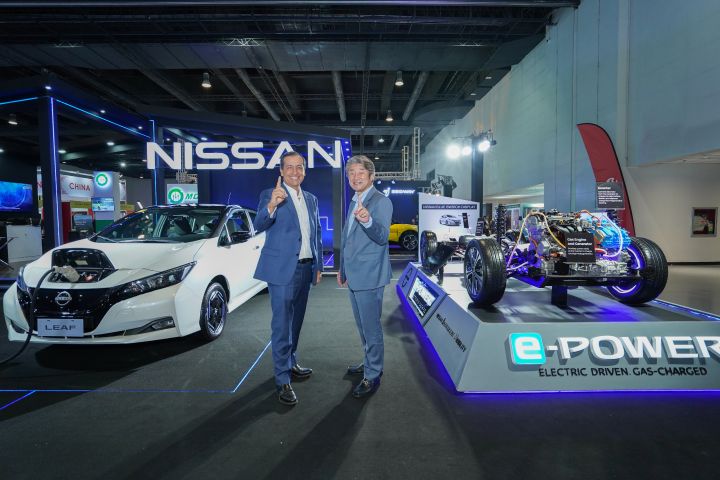 Two guys giving a thumbs up with two vehicles on each side