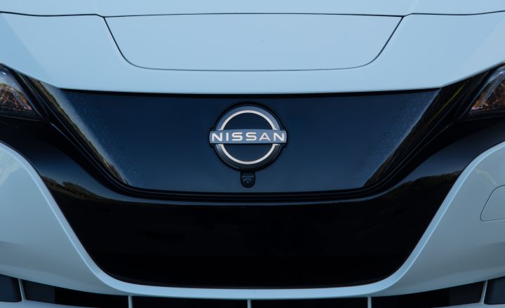 Front close-up view of the Nissan Logo on the grill of a white 2025 Nissan LEAF.