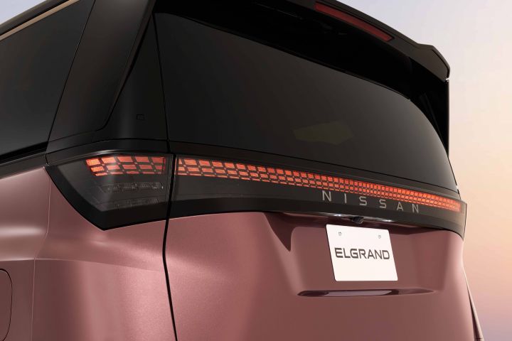 A close-up of the rear exterior of a Fuji-dawn-colored Elgrand. The taillights and rear design details are emphasized.