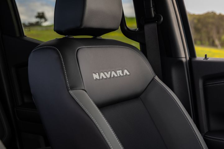 Close-up of a front seat in a 2026 Nissan Navara ST-X, showing black upholstery with contrast stitching and NAVARA embroidery on the upper backrest.