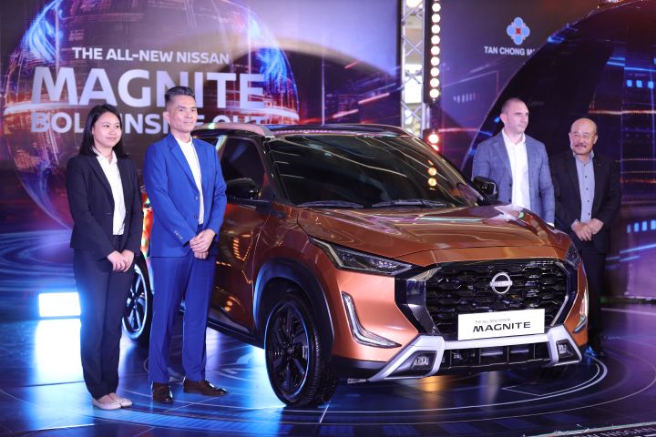 A group photo of representatives from Tan Chong Motor Laos and Nissan and standing on the stage beside the Nissan Magnite