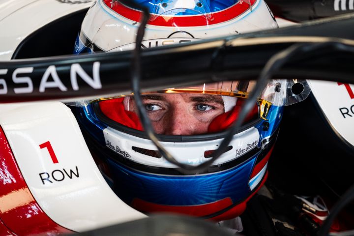 Oliver Rowland mit aufgesetztem Helm und hochgeklapptem Visier sitzt im Auto mit der Nummer 1 in der Teamgarage.
