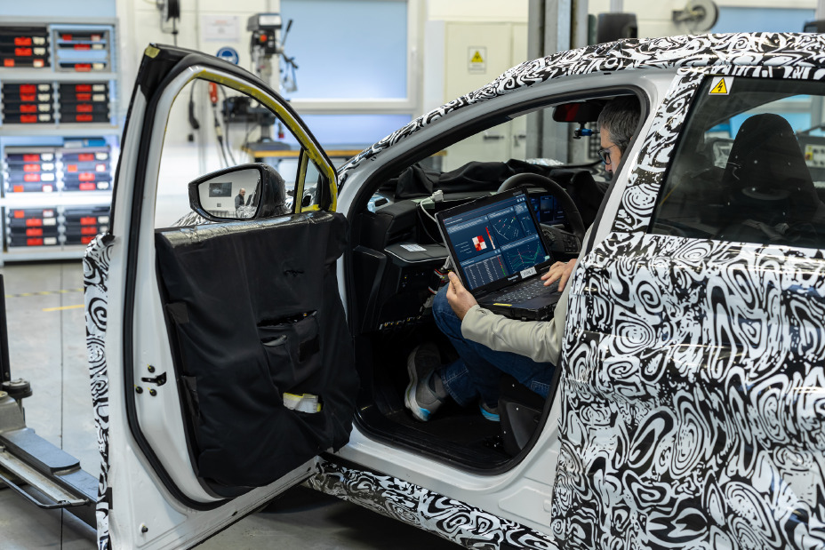 Ein Nissan Ingenieur sitzt in einem getarnten Testfahrzeug und arbeitet an einem Laptop mit der KI-Software von Monoloth.
