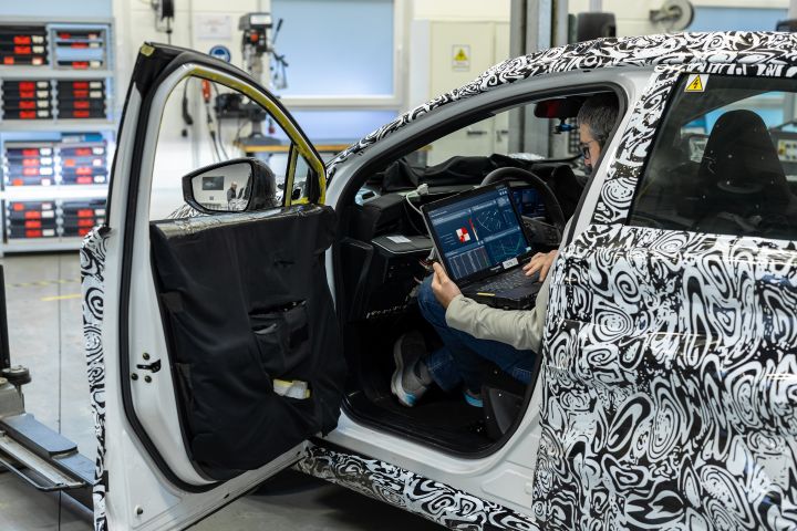 Ein Nissan Ingenieur sitzt in einem getarnten Testfahrzeug und arbeitet an einem Laptop mit der KI-Software von Monoloth.