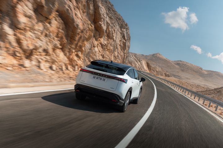 Rear view of white Ariya driving through mountains