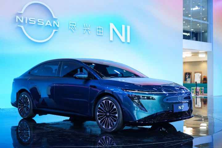 広州モーターショーのステージに展示された東風日産の緑色の新型セダン電気自動車「N7」。背後のスクリーンには日産ロゴ。