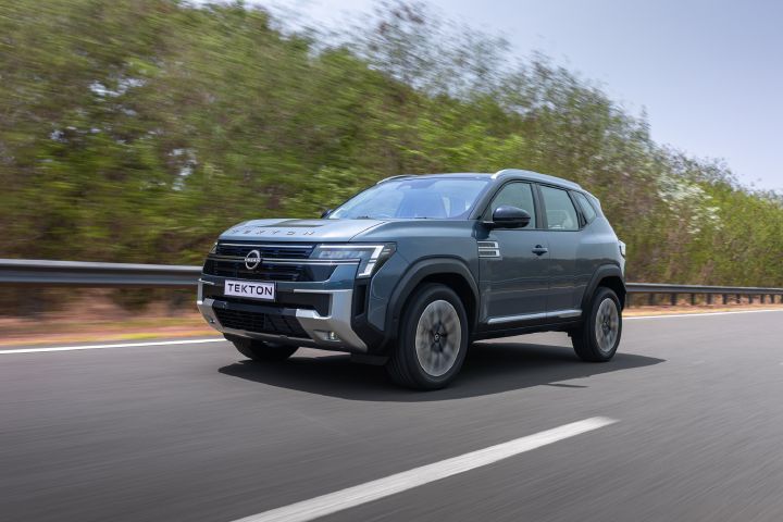 Front three-quarter view of the Nissan Tekton driving along a tree-lined road.