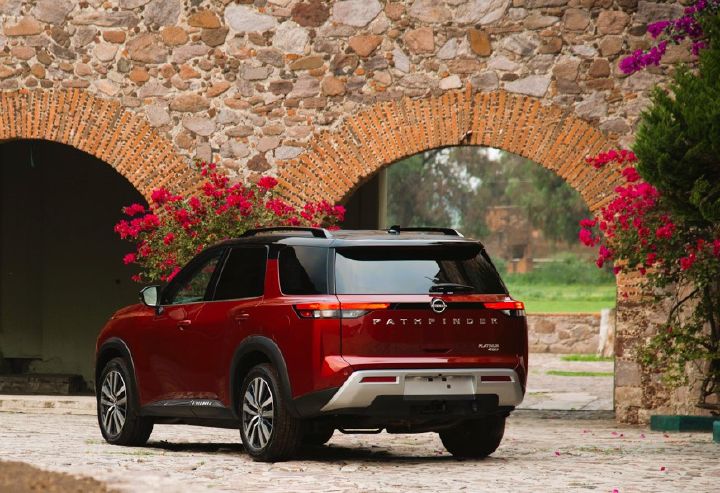 Nissan Pathfinder roja con foto por detrás en hacienda con flores.