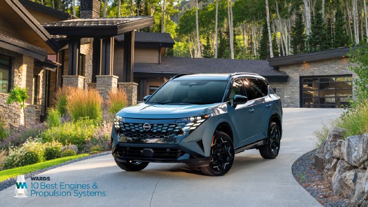 A blue 2027 Nissan Rogue Hybrid parked in ¾ angle in front of a modern, cottage-like home.