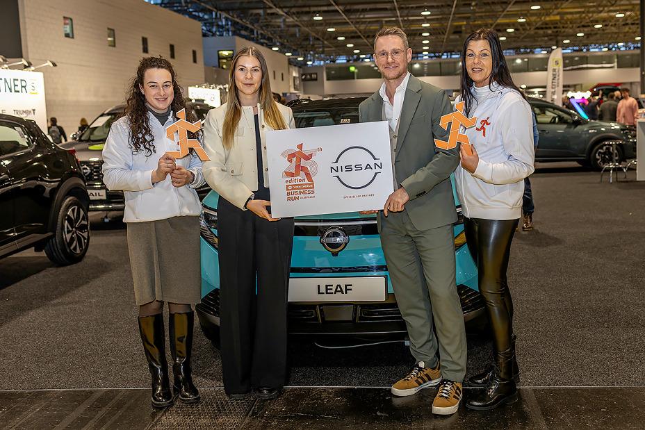 Drei Frauen und ein Mann stehen vor einem türkisfarbenen Nissan LEAF und halten lächelnd eine Tafel vom Wien Energie Business Run in den Händen