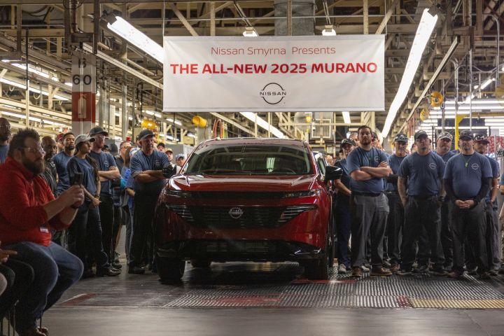 A crowd of workers stand around a red 2025 Nissan Murano and a banner above them that reads "The All-New 2025 Murano".