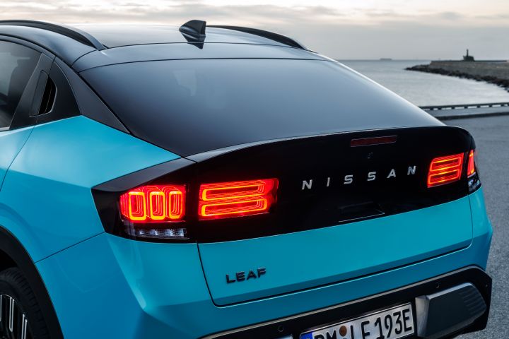 Nahaufnahme vom schwarz abgesetzten Heck des Nissan LEAF mit rot leuchtenden Rücklichtern in der Dämmerung