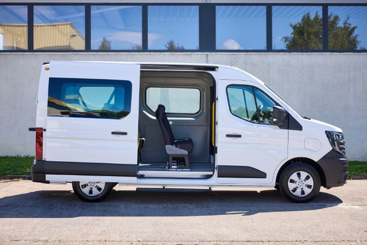 Seitenansicht eines weißen Nissan Interstar-e mit MobiTEC Ausbau mit geöffneter seitlicher Schiebetür, durch die man eine Sitzreihe sieht.