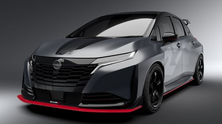 A silver and black two-tone sports car, the Aura Nismo RS Concept, photographed in a studio from a front-left angled view. The vehicle is stationary, featuring a Nissan logo on the center of the front grille and a red accent line with the 'NISMO' logo on the lower bumper. The hood has a black stripe, and the side displays a light gray  'RS.' The background is a simple gray gradient, highlighting the car's sleek design
