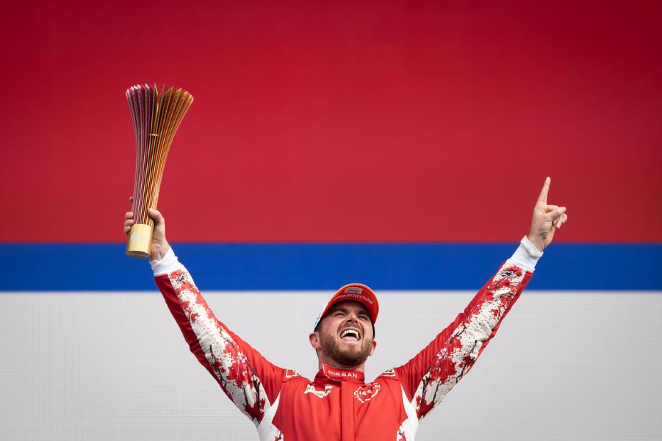 Piloto Oliver Rowland segurando o troféu em gesto de comemoração a sua vitória