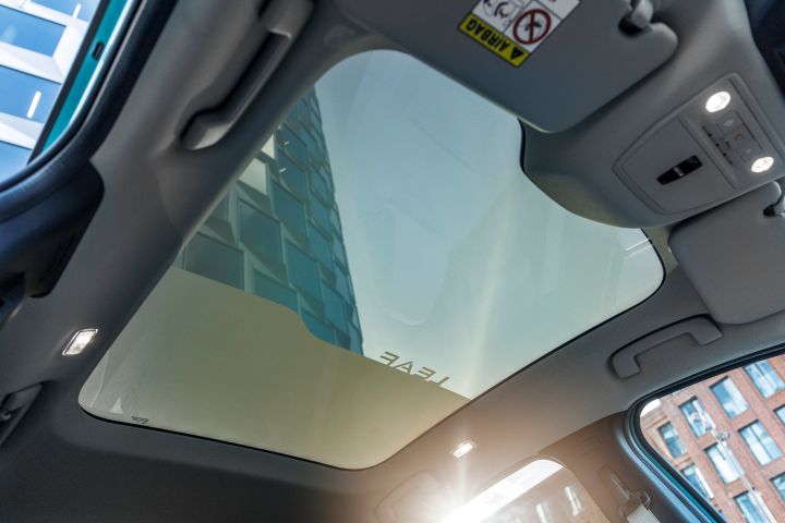 Blick aus dem Innenraum durch das Panoramaglasdach des Nissan LEAF, die Sonne scheint durch das teilweise verdunkelte Glas