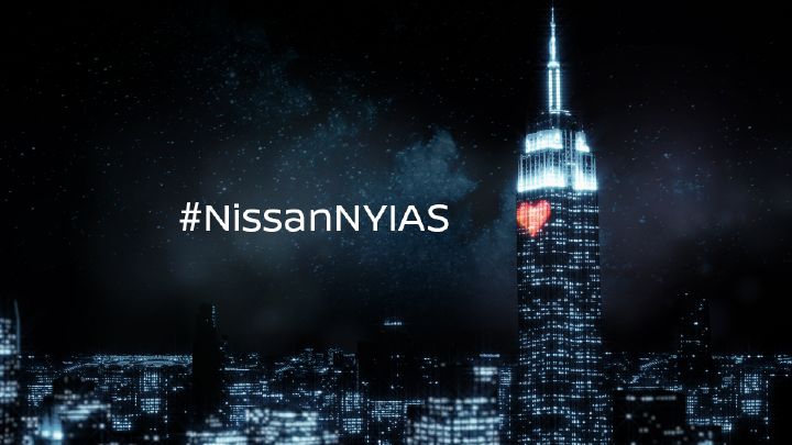 A nighttime cityscape featuring the Empire State Building illuminated with blue lighting and a red heart, accompanied by the hashtag #NissanNYIAS.