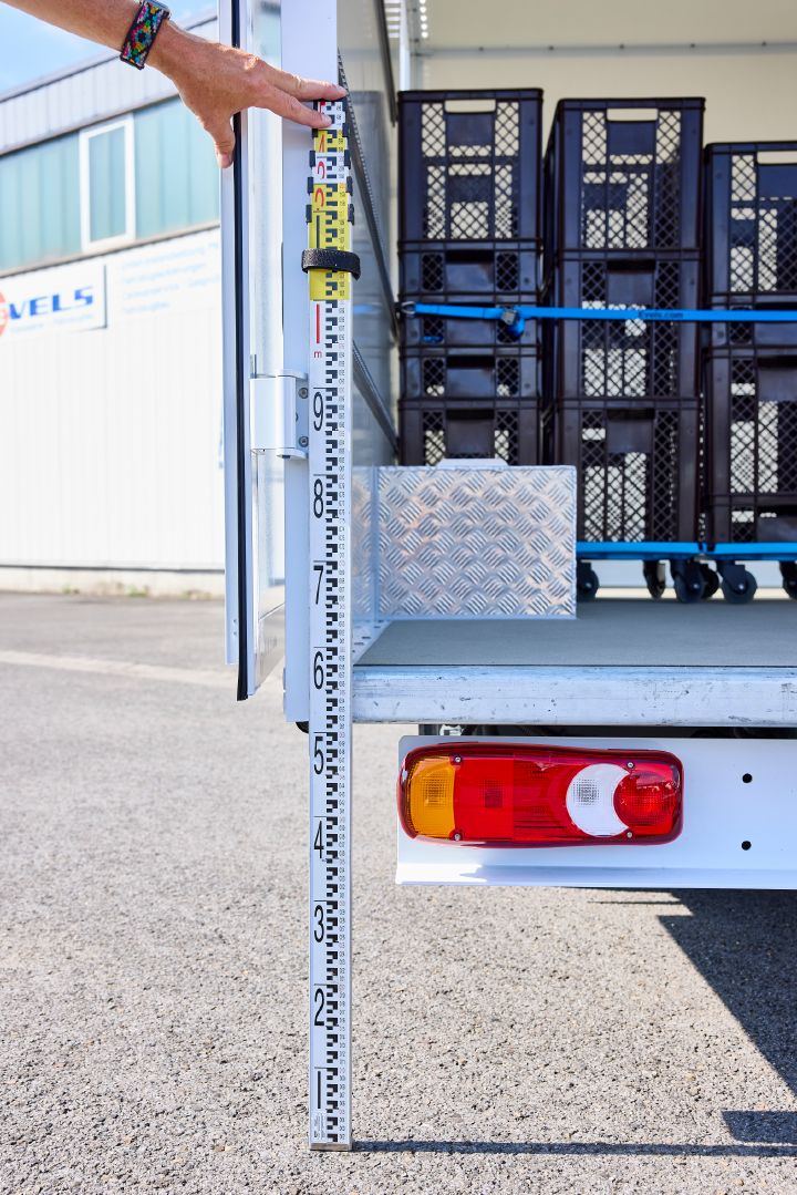 Eine Hand hält ein Zentimetermaß ans Heck des Nissan Interstar-e mit Bäckereikoffer, um die Ladehöhe zu zeigen