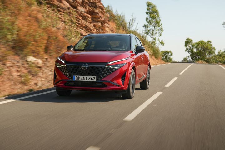 Front view of New refreshed Qashqai 2024 in fuji sunset color driving on a road in Faro, Portugal with front grille and new Nissan logo