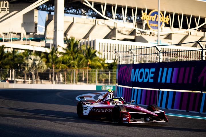 Oliver Rowland im Nissan e‑4ORCE 05 mit der Startnummer 1 auf der Rennstrecke in Miami, mit dem Attack Mode-Logo und dem Hard Rock Stadium im Hintergrund.