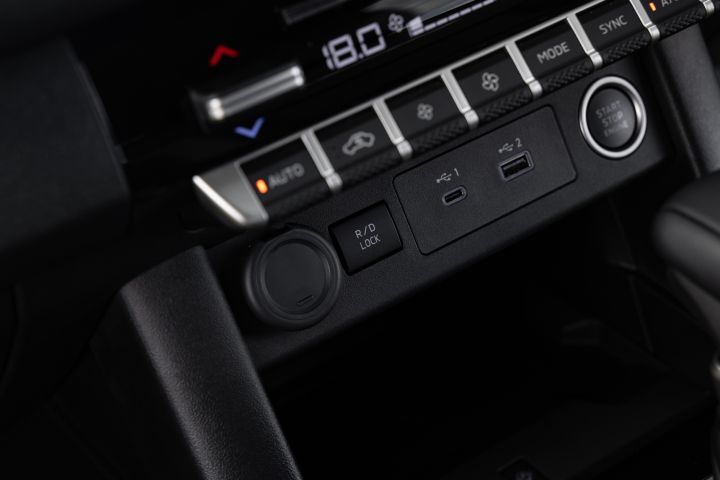 Close-up of the lower centre console in a 2026 Nissan Navara ST‑X, showing dual-zone climate controls, a 12V socket, a locking rear differential switch, USB‑C and USB‑A ports, and the engine start-stop button.