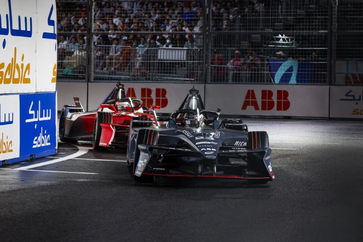 Oliver Rowland auf der Strecke beim E-Prix in Tokio im Nissan Formel E Rennwagen mit der Startnummer 1, wie er nach links in eine Kurve einbiegt, während hinter ihm ein weiteres Auto fährt und im Hintergrund das ABB-Logo zu sehen ist