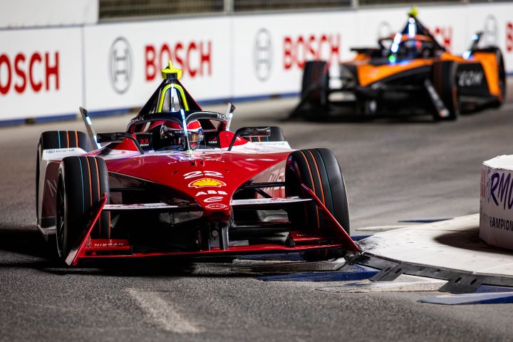 Nissan Formule E Team-coureur Oliver Rowland in zijn raceauto met in de achtergrond een raceauto van het NEOM McLaren raceteam.