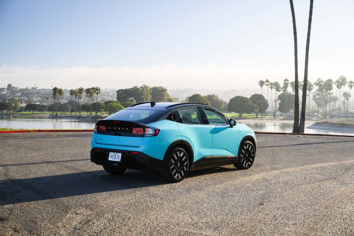 Angled rear view of the 2026 Nissan LEAF parked on asphalt infront of water.