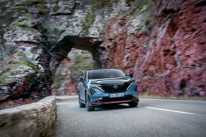Photo dynamique de l’avant de l'Ariya NISMO traversant un tunnel de montagne naturel.