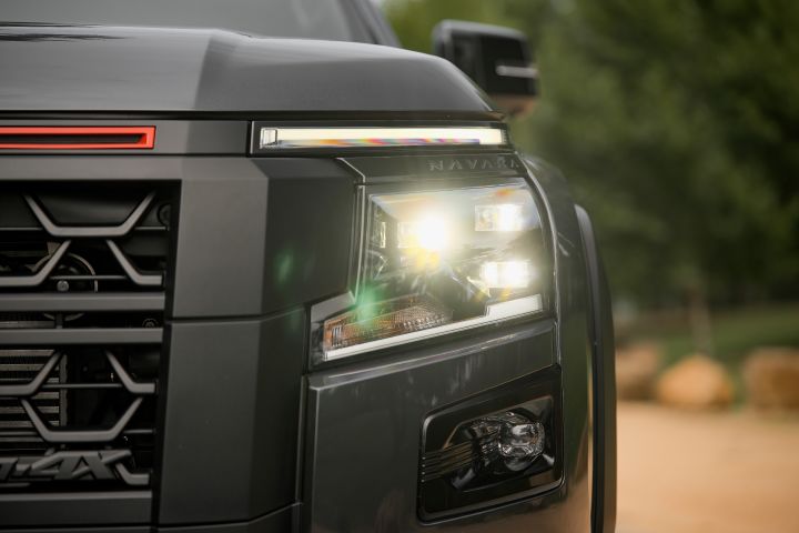 2026 Nissan Navara PRO-4X finished in Boulder Grey showing a low-angle grille close-up with Nissan badge, red accents and PRO-4X branding.