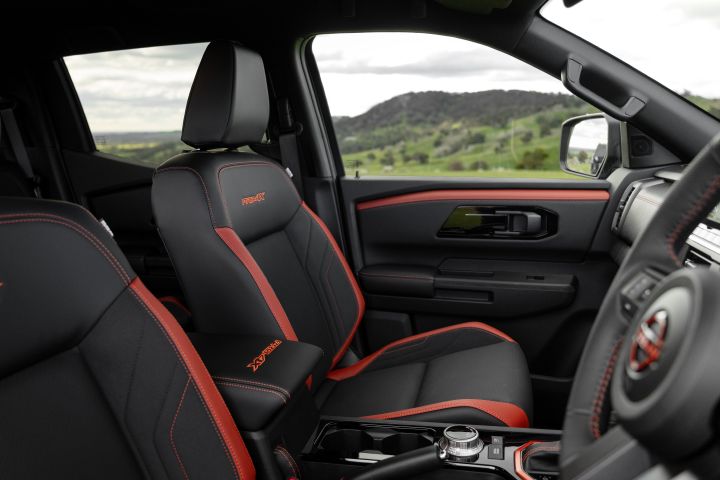 2026 Nissan Navara PRO-4X finished in Boulder Grey presenting the front cabin with red-accented bucket seats, PRO-4X embroidery, centre console and passenger door trim.