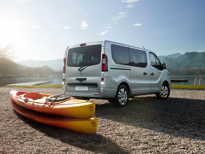 Veículo comercial Nissan PRIMASTAR visto de trás, na lateral, com caiaque ao lado