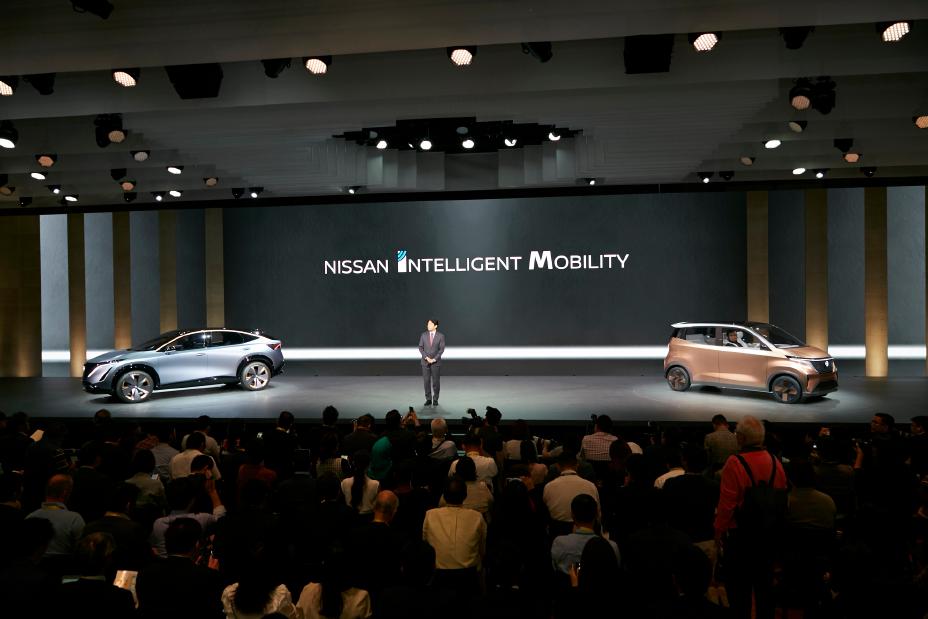 A person on stage with two Nissan concepts at the Tokyo Motor Show Press Conference