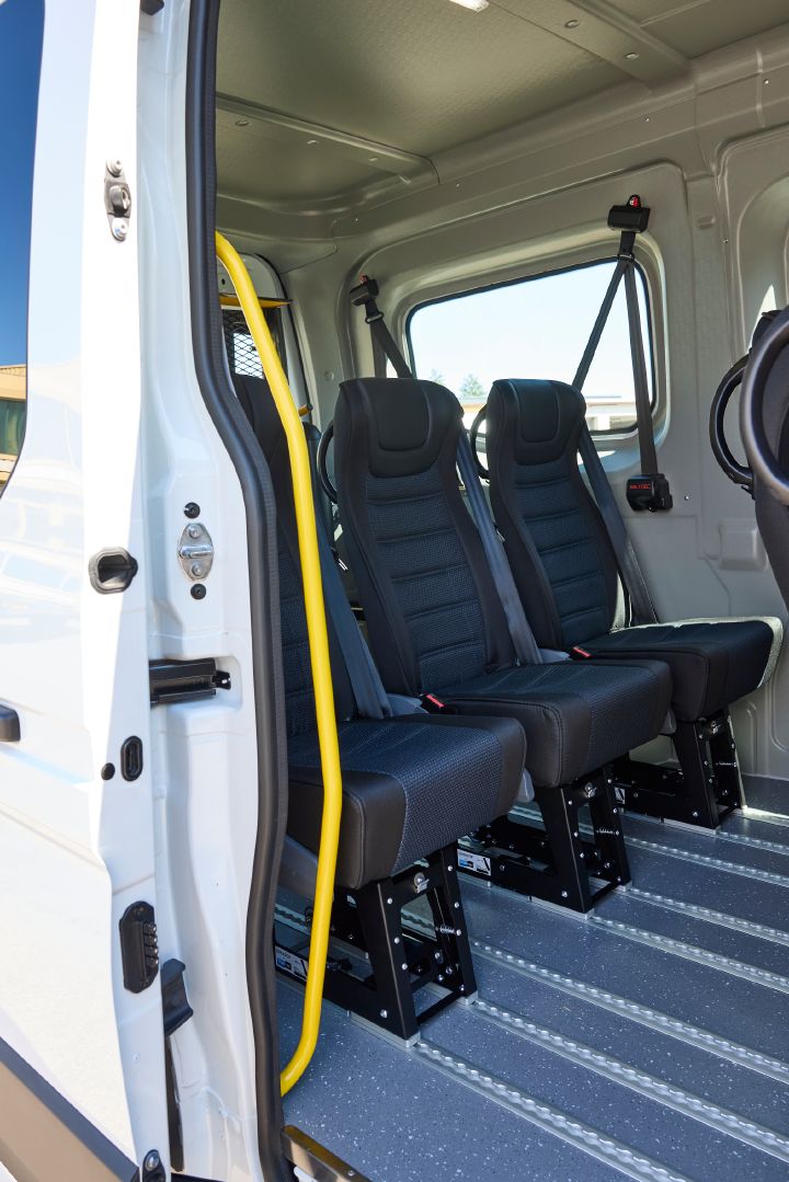 Durch die geöffnete seitliche Schiebetür sind drei Einzelsitze in der dritten Sitzreihe sowie ein gelber Haltegriff im Nissan Interstar-e mit MobiTEC Ausbau zu sehen